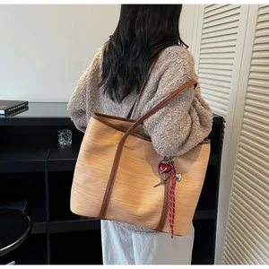 Detail of minimalist tote bag with beige woven texture, brown leather straps and heart charm