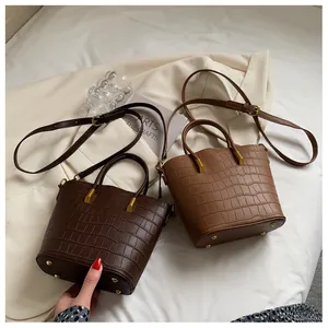 Detail showing vintage crocodile texture bucket bags with metallic studs on a cream fabric