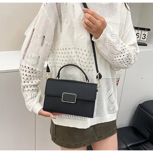 Détail du sac à main en cuir grainé noir avec boucle dorée et poignée ronde