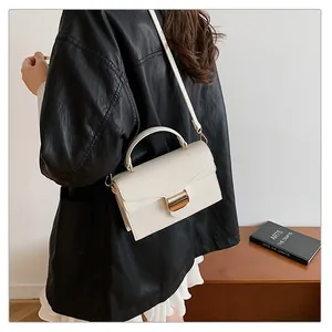 Vue détaillée de la texture du cuir blanc grainé et de la boucle dorée du sac à main