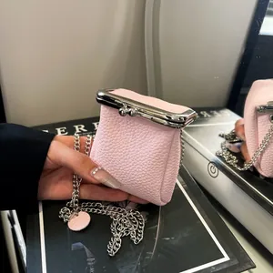 Detailed macro of pink litchi grain leather mini bag with silver metal clasp and chain