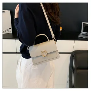Détail du sac à main gris clair texturé litchi avec une boucle en métal doré en U