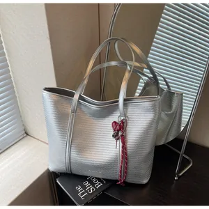 Detailed silver woven tote bag with metallic texture and a small red heart charm