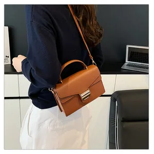 Détail d'un petit sac carré en cuir marron texturé avec boucle dorée et bandoulière fine