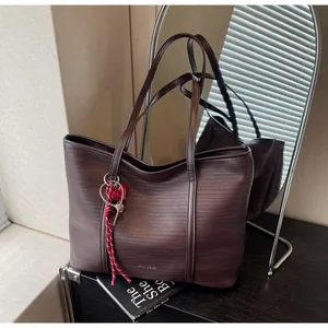Macro detail of dark brown woven tote bag featuring synthetic leather texture and fringe charm