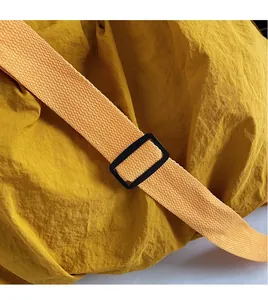 Detail of adjustable orange woven shoulder strap with black buckle on yellow canvas bag