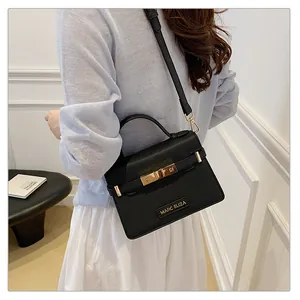Detail view of black leather handbag with gold hardware and MARC ELIZA logo worn by model