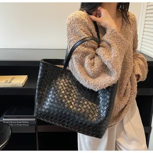 Detail view of a black woven tote bag featuring large Intrecciato pattern for daily use
