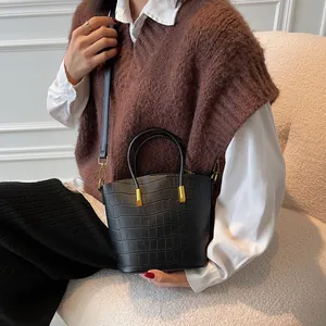 Chic black crocodile embossed bucket bag with gold hardware and top handles
