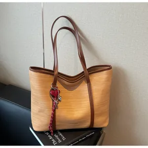 Detail of woven tote bag with brown leather trim and red heart pendant on books