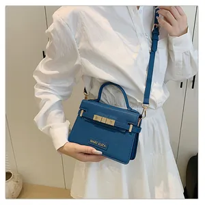 Detailed shot of blue textured leather handbag with gold lock and adjustable strap