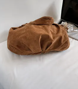 Close-up of a large dark brown suede tote bag with a slouchy design on a white bed