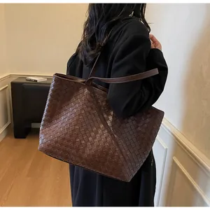 Detail of dark brown woven tote bag showing handcrafted texture and slim shoulder straps