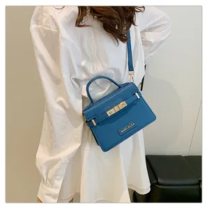 Blue trapezoid handbag with pebble leather texture and gold hardware detail on model