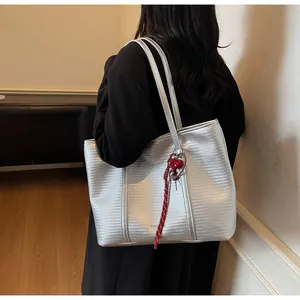 Detail of silver metallic woven tote bag with a red heart pendant and shoulder straps