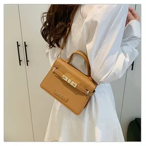 Detailed close-up of a caramel leather handbag with Marc Eliza logo plate and top handle