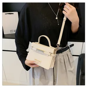 Detail showing the metal logo and belt buckle lock on a cream leather handbag