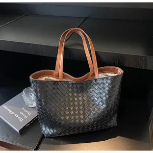 Close-up of black woven leather texture and brown handle detail on the tote bag