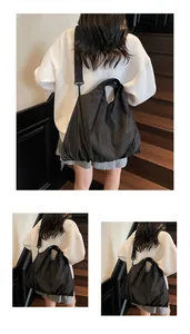 Close-up of black nylon shoulder bag with metal hooks and wide strap detailing
