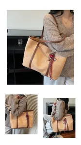 Close-up of woven beige tote bag with brown leather straps and heart charm detail
