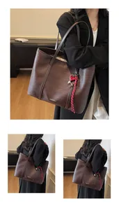 Detailed view of dark brown woven tote bag with red heart charm and shoulder strap