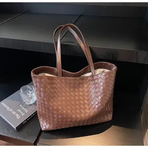 Detailed view of brown woven leather texture on a spacious retro tote bag with thin straps