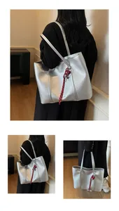 Detail of silver woven tote bag featuring red heart pendant and slim shoulder straps