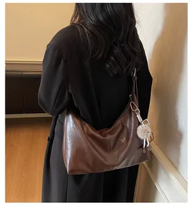 Brown vintage hobo bag in glossy leather with a plush charm shown on the model