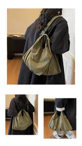 Detail view showing the olive green canvas shoulder bag with pleated texture and wide strap