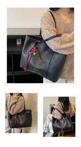 Macro detail of black woven tote bag with heart pendant and white fashion text