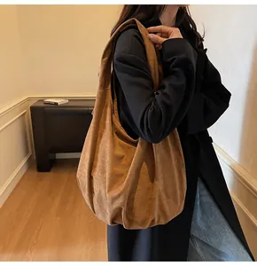 Detailed view of a brown suede hobo tote bag styled with a long black coat