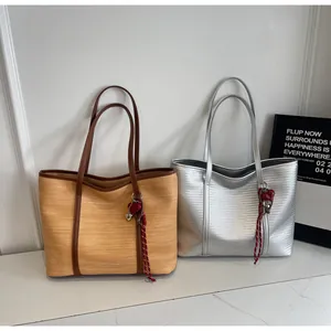 Detail view of khaki woven and silver metallic tote bags with heart charms on marble