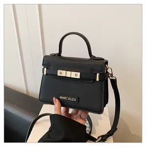 Detail of black crossbody bag with MARC ELIZA logo and textured leather finish