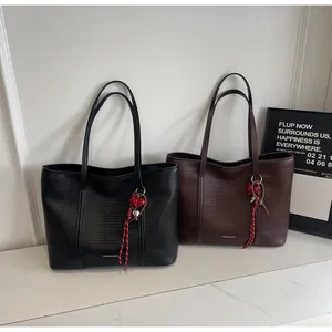 Detail of black and brown tote bags with woven texture and red heart charms