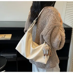 Close-up of minimalist cream white hobo bag in soft PU leather with plush charm