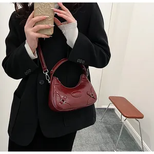 Detail of burgundy glossy leather handbag with silver hardware and vintage patches