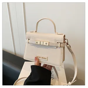Close-up of cream crossbody bag featuring metal buckle and Marc Eliza logo details