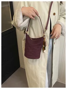 Detail der burgunderroten gesteppten Samt-Eimertasche mit Vintage-Holzperlen-Anhänger