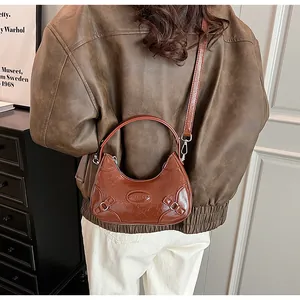 Close-up of vintage brown hobo bag with adjustable strap and embossed oval logo detail