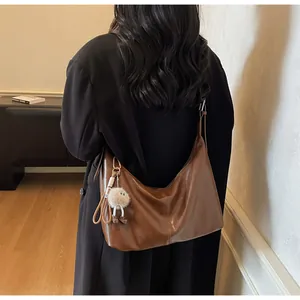 Detail view of large brown tote bag with glossy leather finish and plush pendant charm