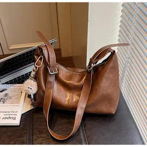 Detailed close-up of brown textured leather tote bag with silver buckle and plush charm