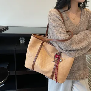 Women's woven tote bag in light brown with dark leather straps and heart charm detail