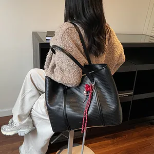 Minimalist black woven tote bag with red heart charm pendant shown in a lifestyle setting