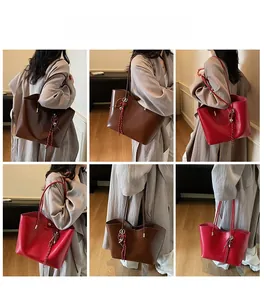 Dettaglio borsa tote grande in pelle cerata con ciondolo a cuore in marrone e rosso