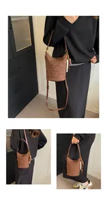 Detail einer dunkelbraunen Stepp-Eimertasche mit matter Textur und dekorativem Anhänger