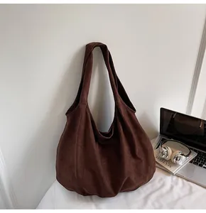 Detail of a dark coffee suede tote bag showing its soft matte texture and large capacity