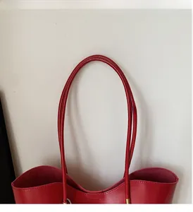 Dettaglio della borsa tote in pelle cerata rossa con manico e fibbia in metallo