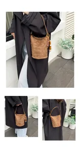 Details einer braunen gesteppten Wildleder-Beuteltasche mit Holzperlen und Schultergurt