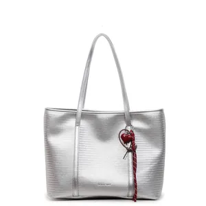 Silver woven tote bag with a metallic finish and red heart pendant on white background