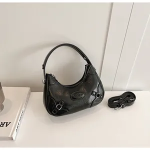 Detail of black glossy oiled leather handbag with silver hardware and logo plaque